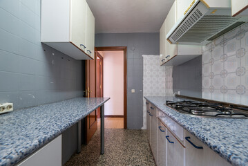 Old kitchen with blue countertops on both sides and dirty terrazzo floors