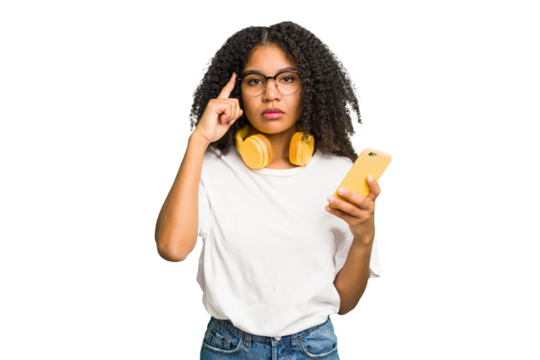 Young african american woman listening to music with yellow headphones isolated pointing temple with finger, thinking, focused on a task.