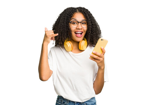 Young african american woman listening to music with yellow headphones isolated showing a mobile phone call gesture with fingers.