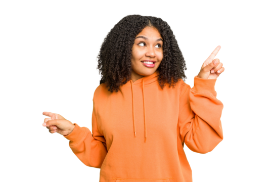 Young african american woman isolated pointing to different copy spaces, choosing one of them, showing with finger.