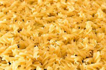 Uncooed Fusilli Pasta - Background. Texture of Bright Golden Dry Macaroni