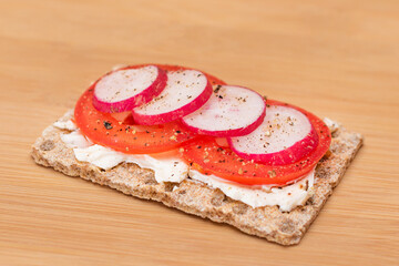 Whole Grain Crispbread with Tomato, Cream Cheese and Radish on Bamboo Cutting Board. Easy Breakfast. Quick and Healthy Sandwiches. Crispbread with Tasty Filling. Healthy Dietary Snack