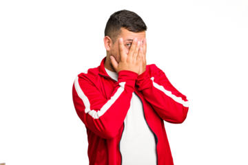 Young caucasian man isolated blink at the camera through fingers, embarrassed covering face.