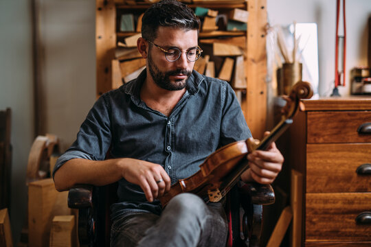 Male luthier with violin in workshop