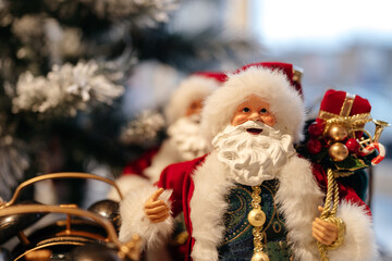 Santa Claus toy close-up on the background of a Christmas tree with a warm lamp light. New Year's and Christmas.