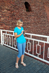 Portrait of a young woman talking on the phone outdoors against a brick wall. The concept of urbanization and communications