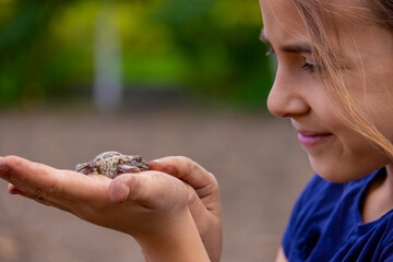 girl hold a toad in the palm of her hand. Selective focus