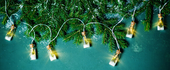 Christmas banner with fir branches and Christmas garland on a green background, top view. Festive new year background.
