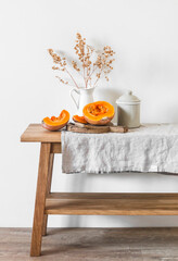 Autumn kitchen still life - cut pumpkin, rustic enamel tableware on a wooden table with a linen tablecloth