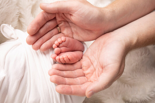 Children's foot in the hands of mother, father, parents. Feet of a tiny newborn close up. Little baby legs. Mom and her child. Happy family concept. Beautiful concept image of motherhood stock photo