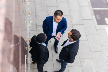 Businesspeople in suits chatting on paved street