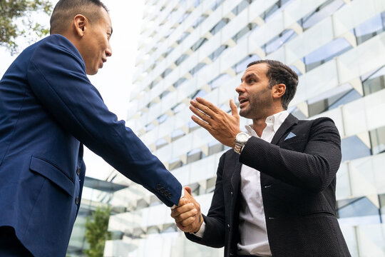 Cheerful businessmen shaking hands on street