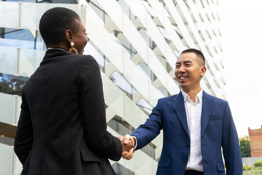 Multiethnic colleagues shaking hands at street