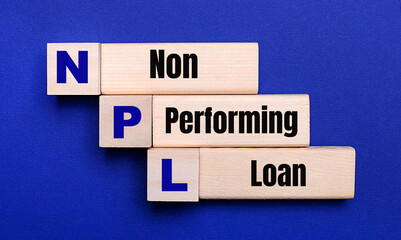 On a bright blue background, light wooden blocks and cubes with the text NPL Non Performing Loan