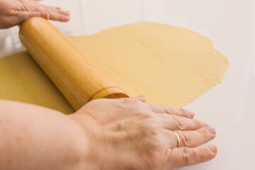 roll out the dumpling dough, old woman roll out wheat egg noodle dough with a wooden rolling pin