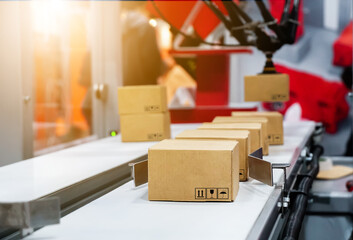 Cardboard boxes on conveyor, robotic arm picked up the blurry box. parcel delivery system concept.