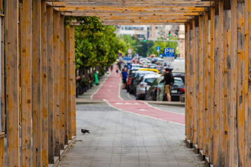 View through a wooden tunnel scaffolding for pedestrian protection with blurred town traffic in the distance