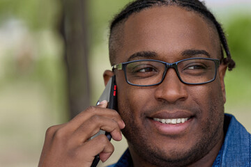 Friendly young man with glasses talks on a cell phone, arranges a meeting with friends. Portrait of...