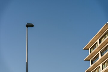 Fototapeta na wymiar Low-angle view of a lamp column by a residential building under the blue sky
