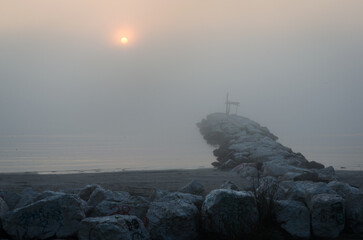 Un frangiflutti della spiaggia del Lido di Venezia con il sole che sorge in una nebbiosa giornata...