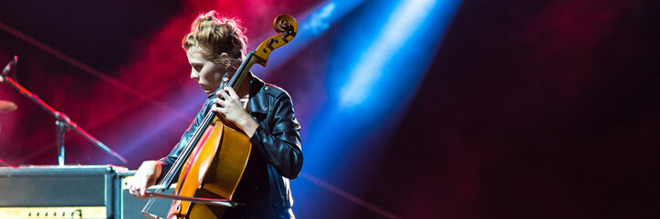 Young woman playing cello on the concert at night