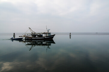 Un peschereccio naviga nelle acque tranquille della laguna di Venezia davanti all'isola di...