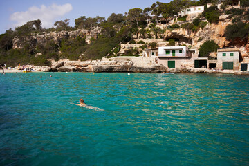 Bañista nada en una playa de color turquesa en el Mediterráneo