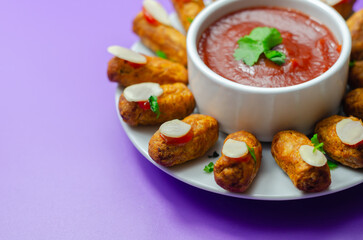 Halloween bloody fingers, pork cocktail sausages decorated with flaked almonds served with tomato and pepper dip