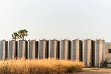 View of metallic industrial storage tanks in a row under the blue sky