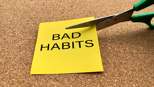 Scissors That Cut Yellow Notepad With Bad Habits Text On A Wooden Desk Background. Spending Concept