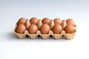 A box of ten fresh eggs. Ten brown eggs in a carton. Eggs. Chicken eggs in a box of cellulose, flesh on protein. Open box with eggs on a white background. 