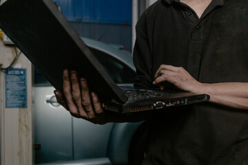 Car mechanic working on laptop in workshop