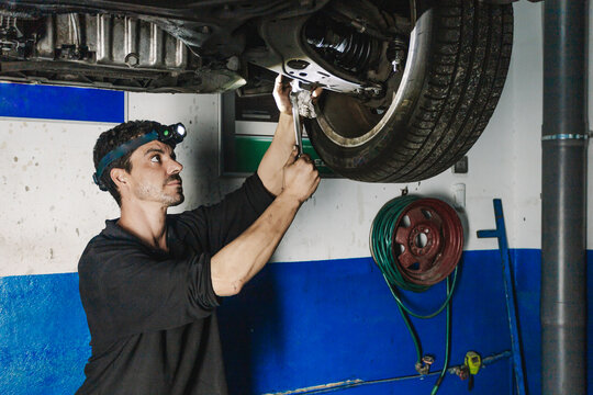 Repairman installing car wheel in workshop