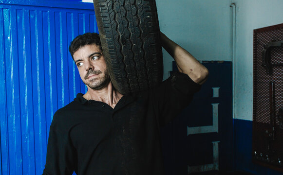 Mechanic with car tire in workshop