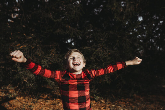 Young boy jumping for joy in Christmas pajamas outdoors