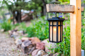 Japanese style hanging lantern lamp light on wooden post in Japan design garden with path at house temple or shrine with and green foliage background and modern decoration