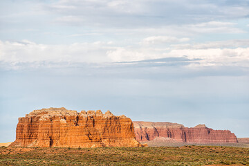 Orange red colored desert butte mesa formations with on horizon near Goblin Valley State Park in Utah in summer day landscape view