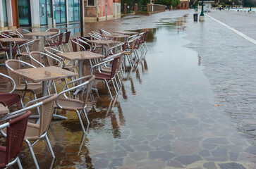 I tavolini di un bar di Venezia sommersi dall'acqua alta  in una giornata nuvolosa di novembre