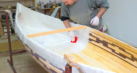 Carpenter making wooden boat of his own design in his workshop - 542481759