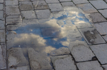 Le nuvole si riflettono in una pozzanghera di pioggia sul selciato di Venezia