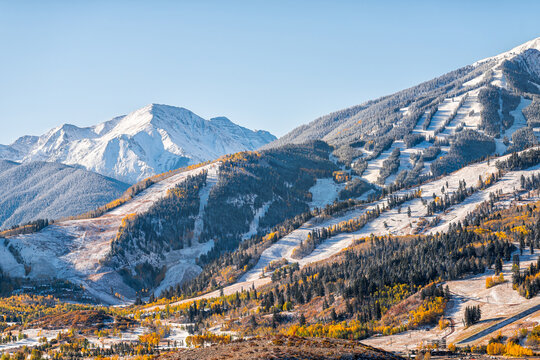 Aspen, Colorado buttermilk ski resort town slopes hill in Rocky mountains view on sunny day with winter snow on yellow foliage autumn trees