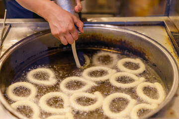 Turkish Dessert Churros Halka Tatli frying in hot oil. Turkish doughnuts or traditional ring sweet - Halka Tatli, kerhane tatlisi.