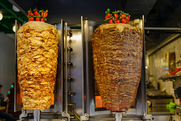 Grilled chicken meat on a vertical rotisserie used in traditional turkish street food Doner Kebab...