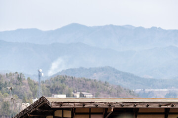 Takayama, Japan Gifu prefecture Japanese town with skyline cityscape of village with TV antenna on houses buildings roof rooftop and mountains in background