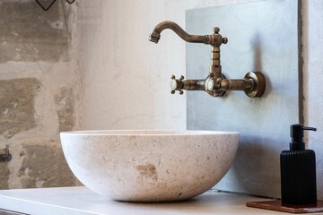Vintage bathroom faucet with a bowl sink and liquid soap in a black container on the right