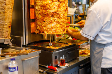 Chef cutting with doner knife Traditional Turkish Doner Kebab meat. Shawarma or gyros. Turkish, greek or middle eastern arab style chicken doner kebab food