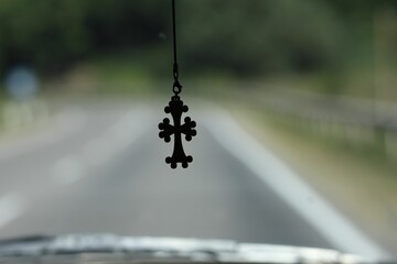 Cross hanging from the rearview mirror of the car, close-up