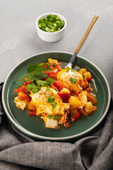 Shakshuka in a frying pan with tomatoes in vegetable sauce with cheese. A dish of fried eggs in a sauce of tomatoes, pepper, onion, garlic and seasonings. Vertical orientation, copy space, close-up
