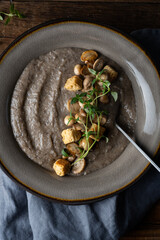Healthy vegan mushroom soup with crackers, made from Button mushrooms and coconut cream, dark rustic background