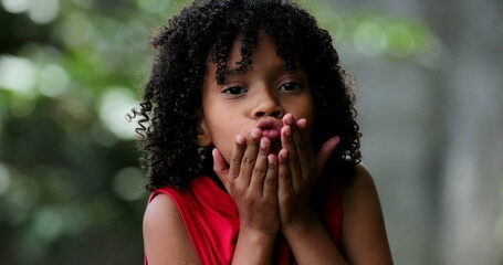 Child sending kisses to camera. Brazilian little blowing kiss